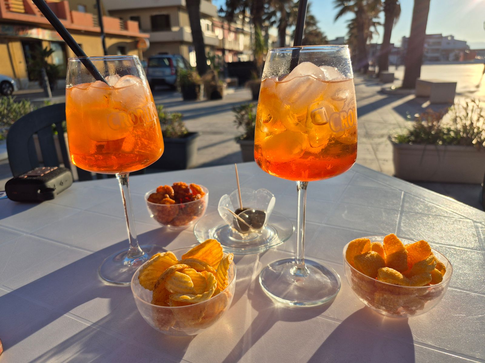 Deux spritz et amuse-bouches sur une table ensoleillée