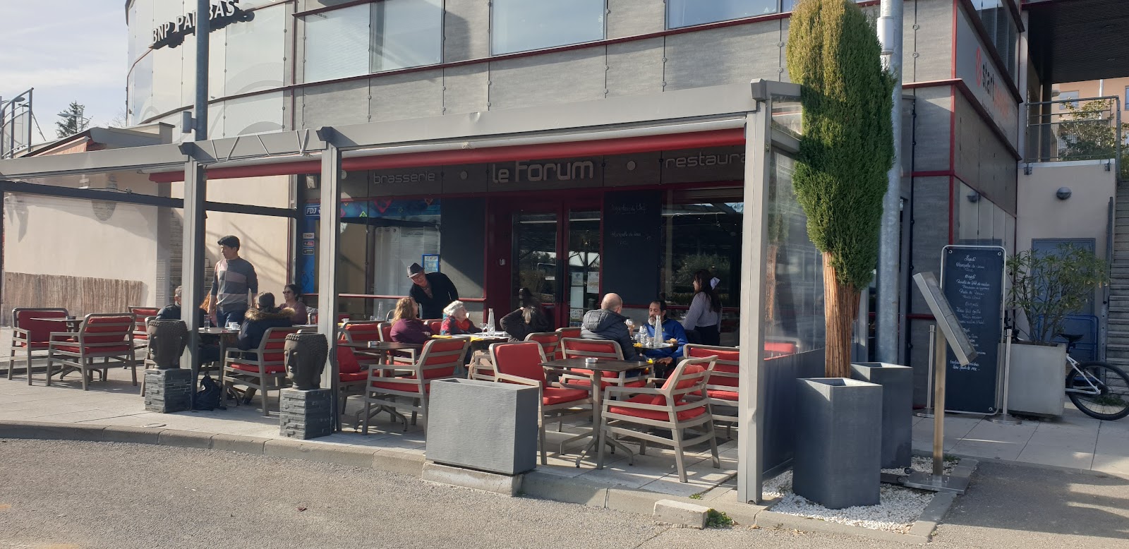 La terrasse du Forum sous sa pergola, tables et fauteuils rouges